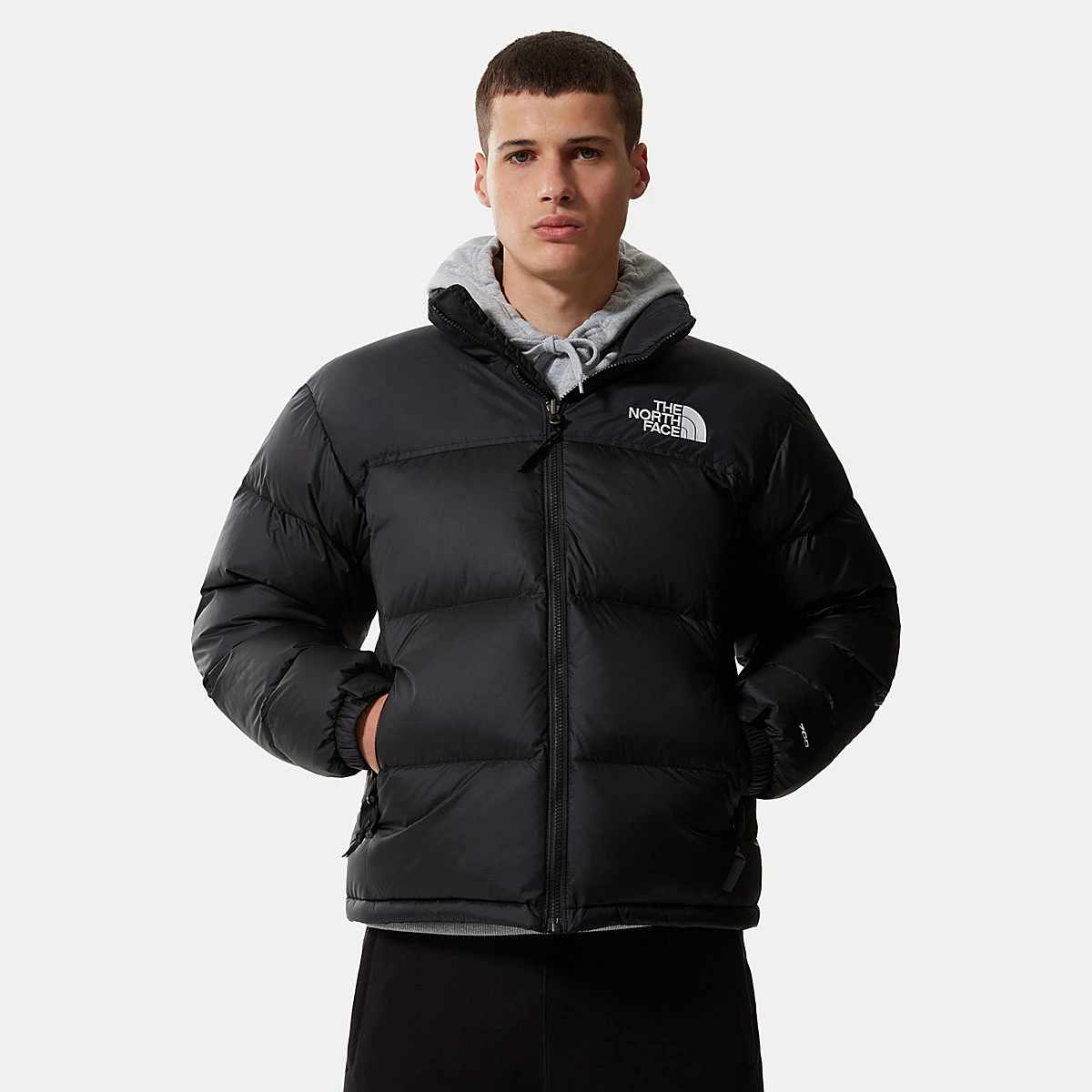 גבר עם ידיים בכיסים לובש מעיל פוך גברים The North Face